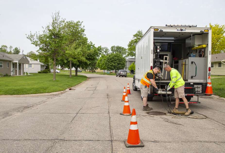City workers Kurtis Herb, right, and Mike Leaven pull equipment back onto their truck after finishing a job in a residential neighborhood of Cedar Rapids, Iowa on Thursday, May 18, 2023. The camera trucks cost around $300,000. (Savannah Blake/The Gazette)